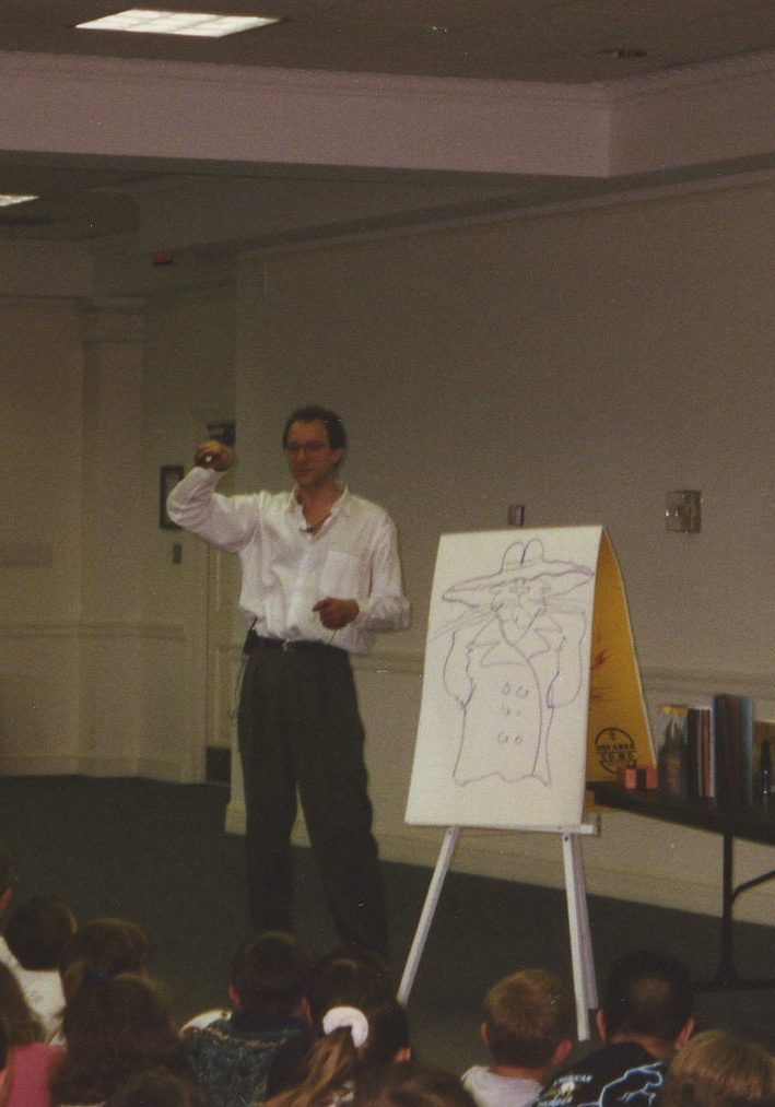 Michael Emberly at a large drawing pad in front of children